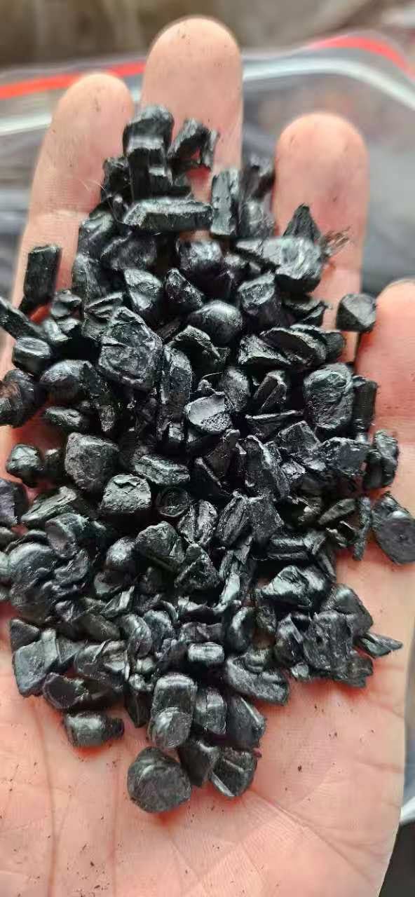 Recycled PC/ABS black regrind flakes in hand