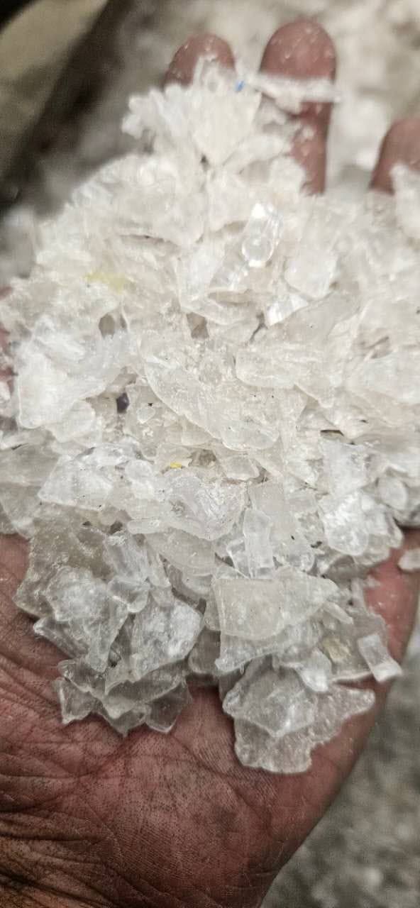Transparent natural PC regrind flakes in hand